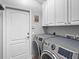 Functional laundry room with front-load washer and dryer and overhead cabinets at 7052 Woodmore Ter, Lakewood Ranch, FL 34202