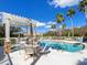 Relaxing pool area with a shaded pergola, comfortable seating, and palm trees under a clear blue sky at 7052 Woodmore Ter, Lakewood Ranch, FL 34202