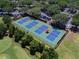 Aerial view of tennis courts with new blue and green surface surrounded by parking and mature trees at 7052 Woodmore Ter, Lakewood Ranch, FL 34202