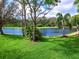 Picturesque backyard with a serene lake view, lush greenery, and mature trees at 7934 Royal Birkdale Cir, Lakewood Ranch, FL 34202