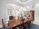 Formal dining room with an elegant chandelier and a view into the living room and screened-in lanai at 7934 Royal Birkdale Cir, Lakewood Ranch, FL 34202