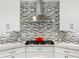 Close-up of a modern gas cooktop with stainless steel vent hood and a decorative backsplash at 7934 Royal Birkdale Cir, Lakewood Ranch, FL 34202