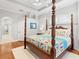 Large main bedroom features a four poster bed, wood floors, and access to an ensuite bathroom at 7934 Royal Birkdale Cir, Lakewood Ranch, FL 34202