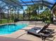 A screened in pool with a spa and two lounge chairs sits on a stone deck at 7934 Royal Birkdale Cir, Lakewood Ranch, FL 34202