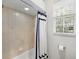 Cozy bath and shower with tile surround, window, and white and blue curtain at 7934 Royal Birkdale Cir, Lakewood Ranch, FL 34202