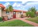 Patio featuring brick pavers, lawn, mature shrubbery, and a red door at 9527 Azure Cv, Bradenton, FL 34210