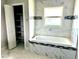 Luxurious soaking tub with a tiled surround, complemented by built-in storage and a window at 1056 Tampa Rd, Venice, FL 34293