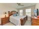 Bedroom featuring a dark wooden bed frame, ceiling fan, and two large windows at 11607 Meadowgate Pl, Bradenton, FL 34211
