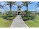 Inviting clubhouse entrance framed by swaying palm trees and lush greenery, creating a welcoming ambiance at 11607 Meadowgate Pl, Bradenton, FL 34211