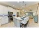 Bright kitchen featuring white cabinets, stainless steel appliances, and an island with seating and views to the living room at 11607 Meadowgate Pl, Bradenton, FL 34211