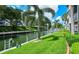 Scenic waterfront view with lush green lawn, mature palm trees, and a canal at 1350 N Portofino Dr # 108, Sarasota, FL 34242