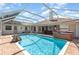 Enclosed in-ground pool with brick patio, hot tub, and view of the home's exterior at 1730 Hudson St, Englewood, FL 34223