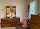 Bedroom view of a wooden dresser with a large mirror, along with a chair and visible bedroom decor at 3002 Vivienda Dr # 22, Bradenton, FL 34207