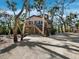 Exterior view of elevated beach home surrounded by tropical foliage and mature landscaping at 3376 S Seclusion Dr, Sarasota, FL 34239