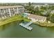 An aerial view of a condo building overlooking a pond with a dock, a pool, and lush landscaping at 3424 Lake Bayshore Dr # 405, Bradenton, FL 34205