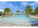 Zero entry pool with lounge chairs and tables surrounded by swaying palm trees and manicured landscaping at 3442 Chestertown Loop, Bradenton, FL 34211