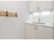 Well-lit laundry room sink featuring quartz countertop and wooden coat rack at 3442 Chestertown Loop, Bradenton, FL 34211
