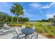 Outdoor seating area with a round table, chairs and lounge chairs, overlooks a lake and lush landscaping at 3442 Chestertown Loop, Bradenton, FL 34211