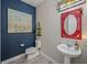 Stylish powder room featuring a red mirror frame, artwork, and a modern pedestal sink at 3442 Chestertown Loop, Bradenton, FL 34211