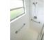 Accessible shower with white tile, grab bars, window and honeycomb floor at 4018 Oakhurst Dr # 3181, Sarasota, FL 34233
