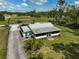 A high angle view of a charming house with a screened-in porch surrounded by lush greenery and a gravel driveway at 4116 34Th E Ave, Bradenton, FL 34208