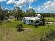 Wide angle of a single story home on a large lot with mature trees and shrubs with an outbuilding in the distance at 4116 34Th E Ave, Bradenton, FL 34208