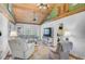 A living room with a wood ceiling, tile floors, comfy seating, and a view of the kitchen at 4116 34Th E Ave, Bradenton, FL 34208