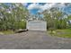 Exterior of an outbuilding with a large garage door and gravel driveway in a wooded backyard setting at 4116 34Th E Ave, Bradenton, FL 34208
