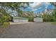 Two outbuildings with garage doors and concrete or gravel driveways in a wooded backyard setting at 4116 34Th E Ave, Bradenton, FL 34208