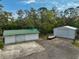 Aerial view of outbuildings with a green-roofed barn, gravel driveway, and mature trees providing privacy at 4116 34Th E Ave, Bradenton, FL 34208