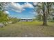 View of the white home with a metal roof and a spacious grassy yard surrounded by mature trees at 4116 34Th E Ave, Bradenton, FL 34208