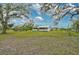 View of the home from a large grassy front yard featuring mature trees, green foliage, and blue sky at 4116 34Th E Ave, Bradenton, FL 34208