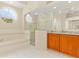 Bright bathroom with a glass enclosed shower and tub with a large round window at 4173 Hearthstone Dr, Sarasota, FL 34238