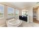 Bright bathroom with garden tub, tile flooring, vanity, and view to the living room at 4789 Vasca Dr, Sarasota, FL 34240