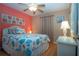 Coastal themed bedroom with coral accent wall, ceiling fan, and wicker nightstand at 5110 76Th E St, Bradenton, FL 34203