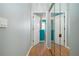 Hallway view with wood floors and white trim leading to brightly colored turquoise bathroom at 5110 76Th E St, Bradenton, FL 34203