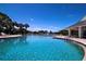 Community pool overlooking a lake with fountain, palms, clubhouse, and lounge seating at 5110 76Th E St, Bradenton, FL 34203