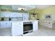White kitchen with island, white appliances, cabinets, and view into adjacent living space with sofa and natural light at 5250 Hyland Hills Ave # 1514, Sarasota, FL 34241