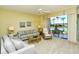 Airy living room boasts comfortable sofas, lanai access and serene water views at 5250 Hyland Hills Ave # 1514, Sarasota, FL 34241