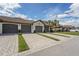 View of condo garages featuring brick paver driveways, lush green landscaping, and a tile roof at 5517 Palmer Cir # 203, Bradenton, FL 34211