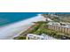 A coastal condo building sits alongside white sands and ocean views, showcasing the beauty of beachside living at 5740 Midnight Pass Rd # 402, Sarasota, FL 34242