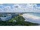 An aerial view of the condominium complex next to a tranquil beach with crystal blue water and a clear sky at 5740 Midnight Pass Rd # 402, Sarasota, FL 34242
