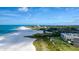 An aerial view shows this beachfront condo with stunning beach access, beautiful blue ocean waters and clear blue sky at 5740 Midnight Pass Rd # 402, Sarasota, FL 34242
