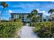 Building exterior view from a sandy path, showcasing well-maintained landscaping at 5740 Midnight Pass Rd # 402, Sarasota, FL 34242