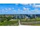 An impressive condominium exterior showcases lush landscaping, manicured grounds and a pathway to a private beach at 5740 Midnight Pass Rd # 402, Sarasota, FL 34242