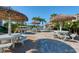 Charming picnic area with thatched umbrellas, tables, and benches surrounded by tropical landscaping at 5740 Midnight Pass Rd # 402, Sarasota, FL 34242