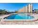 Inviting outdoor pool area with lounge chairs, tables, and lush landscaping under clear blue sky at 5740 Midnight Pass Rd # 402, Sarasota, FL 34242