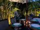 Elegant outdoor dining setup with table setting for an evening dinner, illuminated by ambient backyard lighting at 5802 De Palmas Ave, Holmes Beach, FL 34217