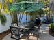 Charming outdoor dining area with seating for six under a leafy umbrella and a lush tropical setting at 5802 De Palmas Ave, Holmes Beach, FL 34217