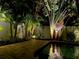 Night shot of a pool with surrounding tropical plants, enhanced by warm and inviting landscape lighting at 5802 De Palmas Ave, Holmes Beach, FL 34217